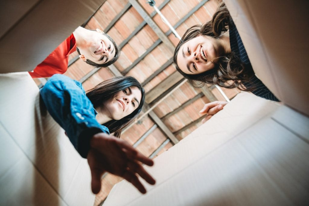 Three people look inside of a box.