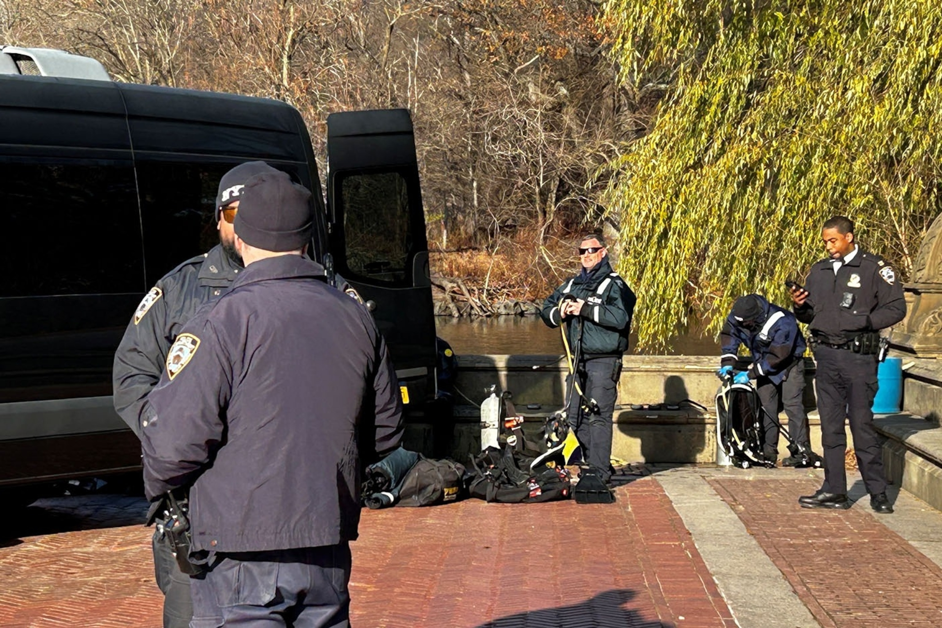 NYPD officers search a pond in Central Park for evidence related to the Brian Thompson shooting.