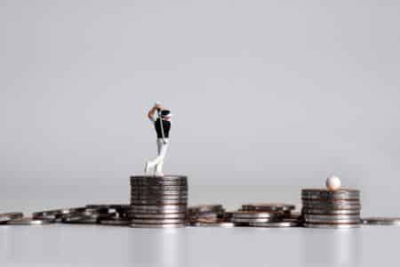 A golfer figurine standing on a stack of coins, symbolizing golf earnings