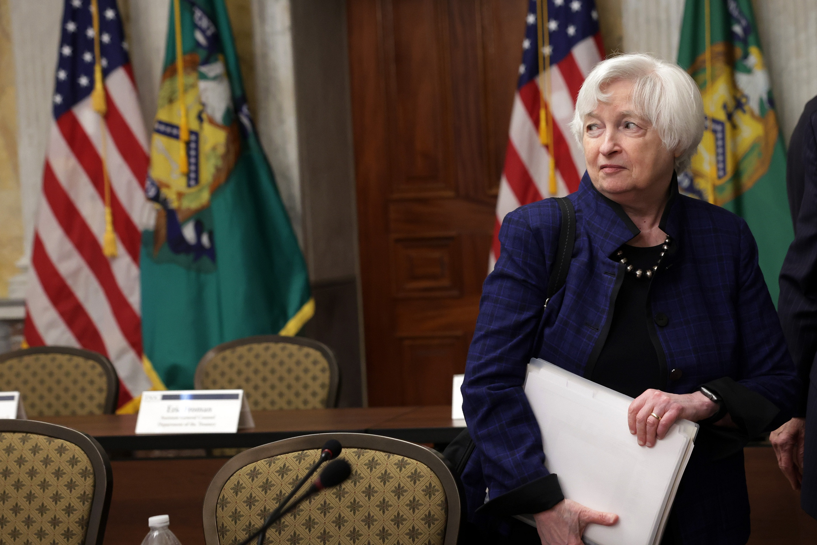 Janet Yellen speaking at a podium with the U.S. Treasury seal visible.