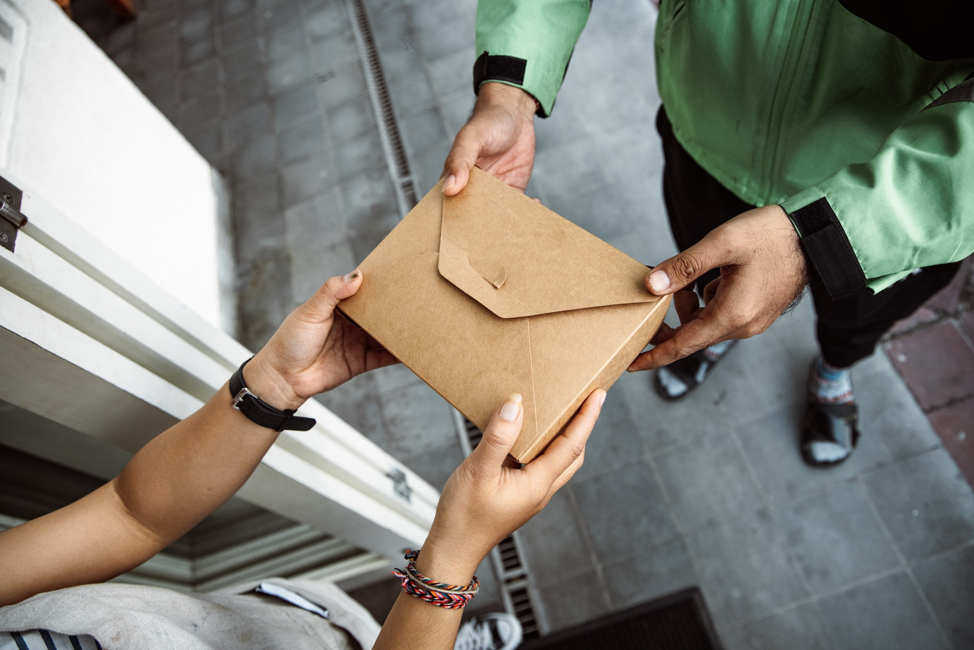 Food delivery driver handing order to customer, illustrating making extra money through gig economy jobs.