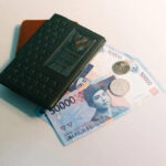 Close-up view of Indonesian Rupiah banknotes, a brown wallet, and a dark passport, illustrating the essential items needed when dealing with Indonesian money.