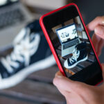 A person takes a photo of a sneaker with a mobile phone