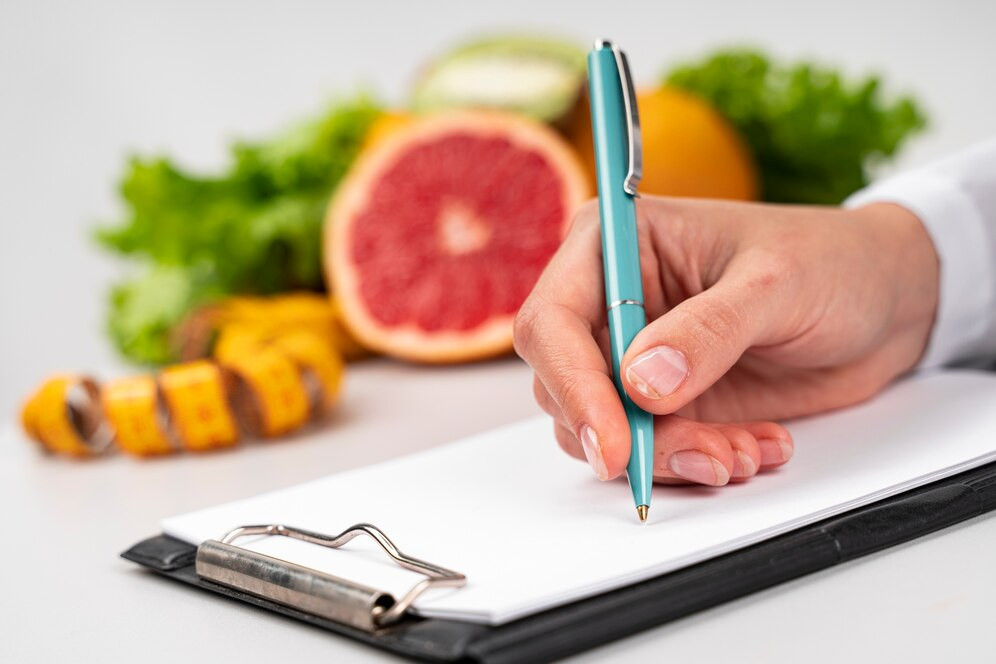 A woman’s hand writing meal plans during a nutrition advice visit. Source: Freepik