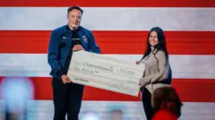 Elon Musk presents a one million dollar check during a town hall
