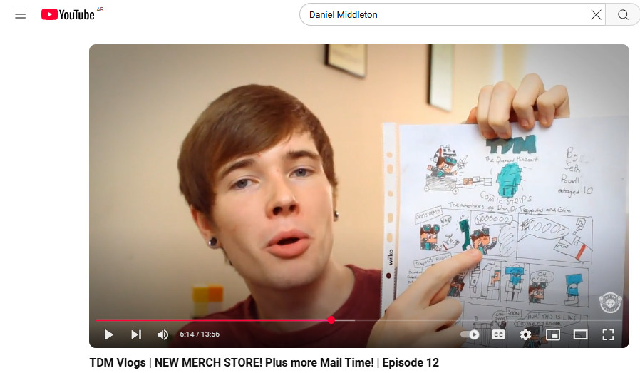 DanTDM showcasing his Minecraft-themed merchandise, including t-shirts and hoodies