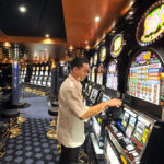Cruise ship employee cleans a slot machine onboard MSC cruises’ Magnifica in Saint-Nazaire, showcasing an onboard revenue stream
