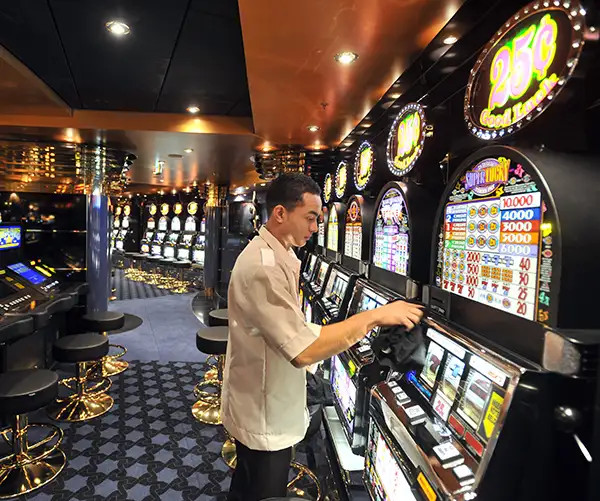 Cruise ship employee cleans a slot machine onboard MSC cruises’ Magnifica in Saint-Nazaire, showcasing an onboard revenue stream