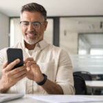 A person holding a phone with money falling out of it.