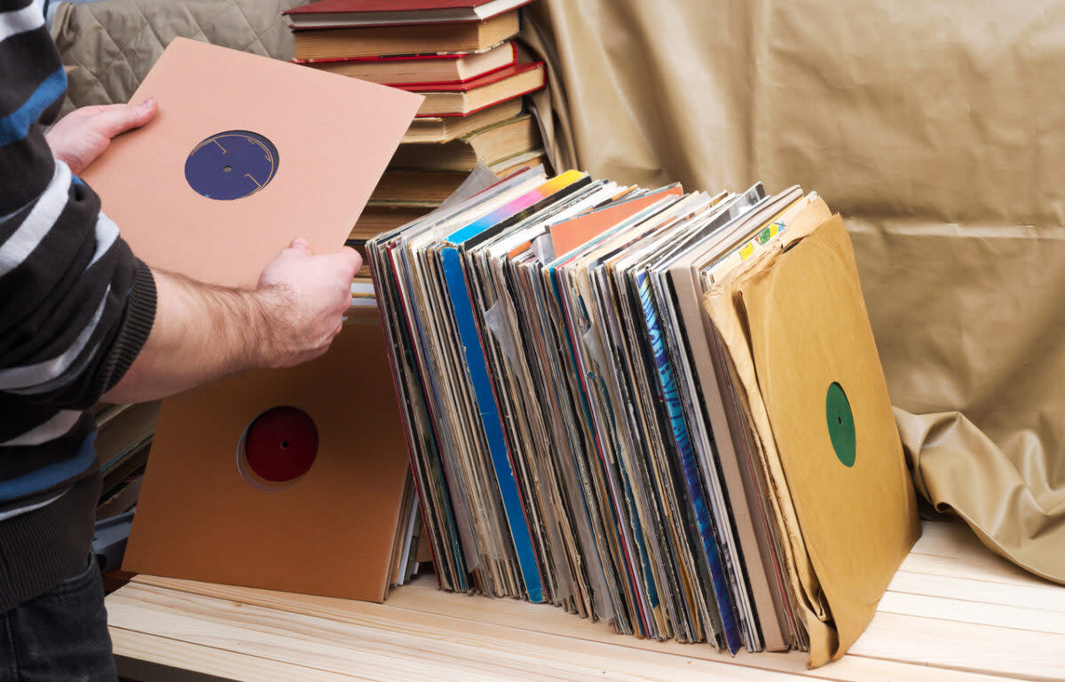 A person is selecting a vinyl record from a large collection in cardboard sleeves, showcasing the joy of discovery and the potential value of each record.