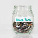Glass jar half-filled with coins and labeled