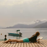 Women lying on dock next to lake
