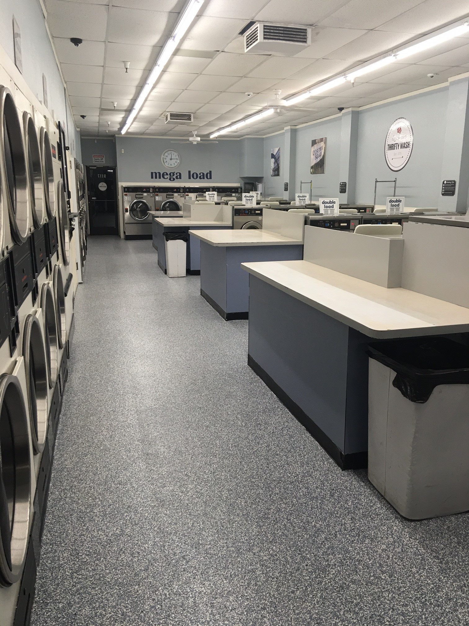 Interior of a modern laundromat with rows of washing machines and dryers.