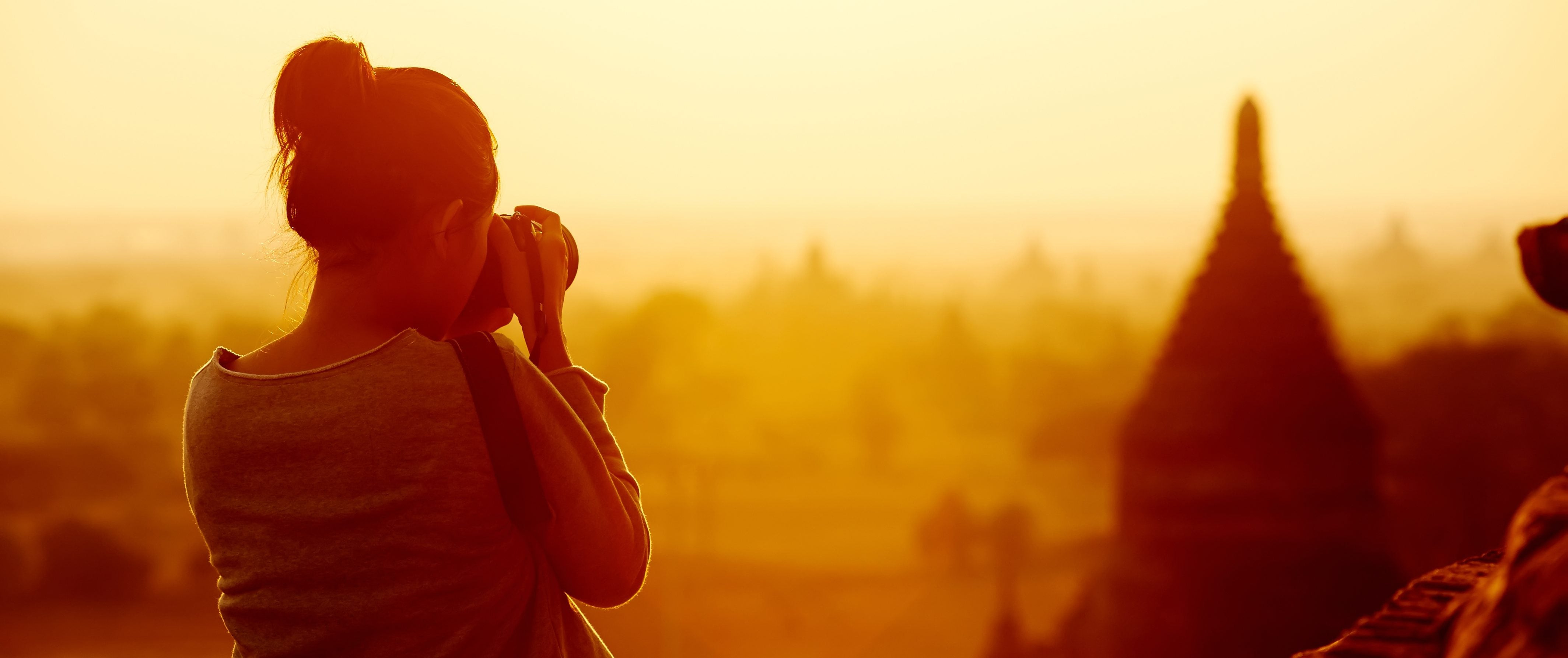 A woman taking pictures of a city skyline, symbolizing exploration and new opportunities.