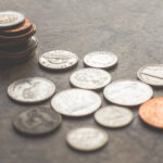 Assorted silver and gold colored coins on gray surface.