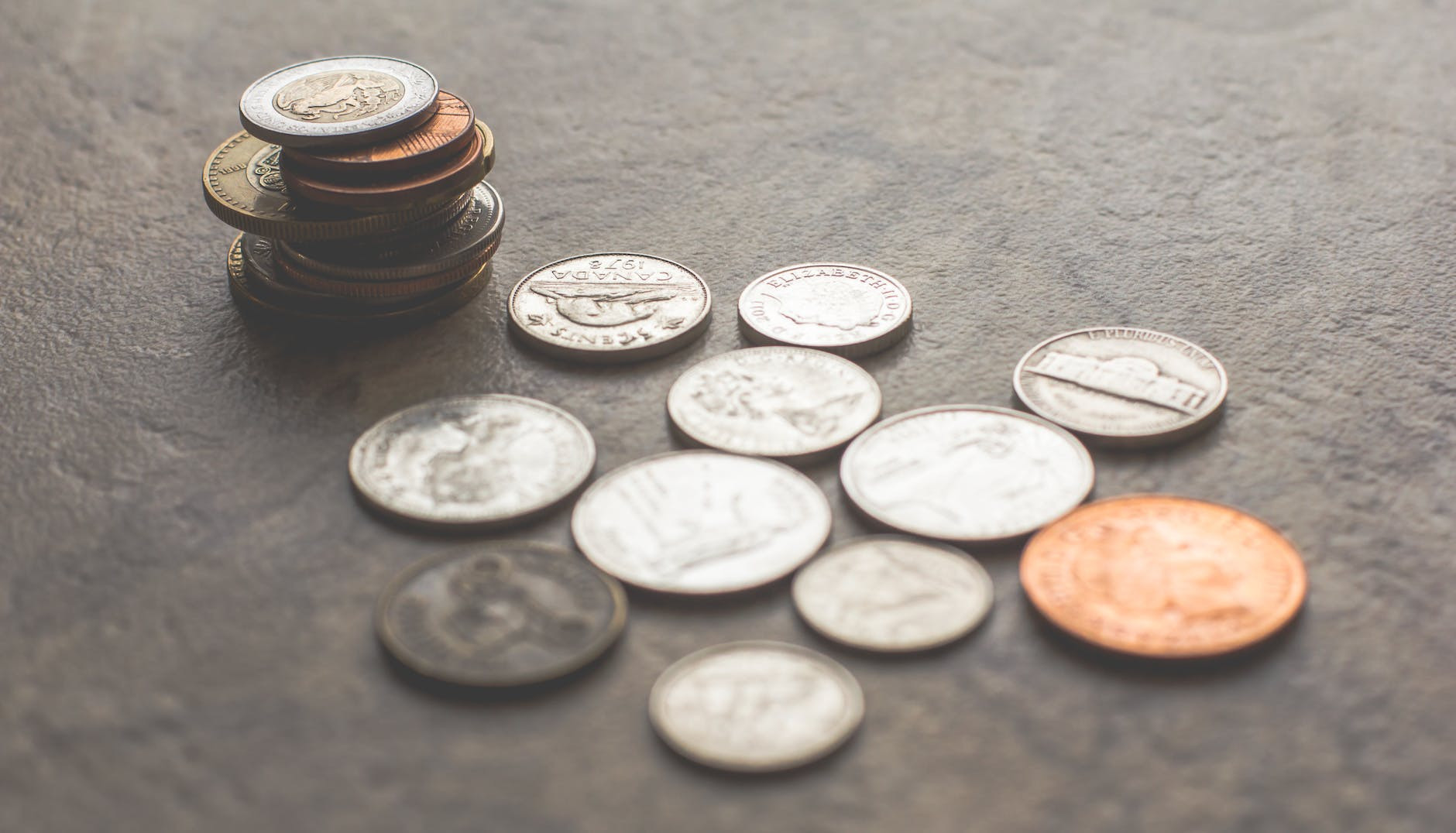 Assorted silver and gold colored coins on gray surface.