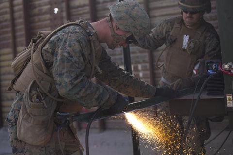 Military support welders in action, repairing equipment in a field setting