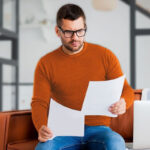 Man sitting on a couch reviewing business documents