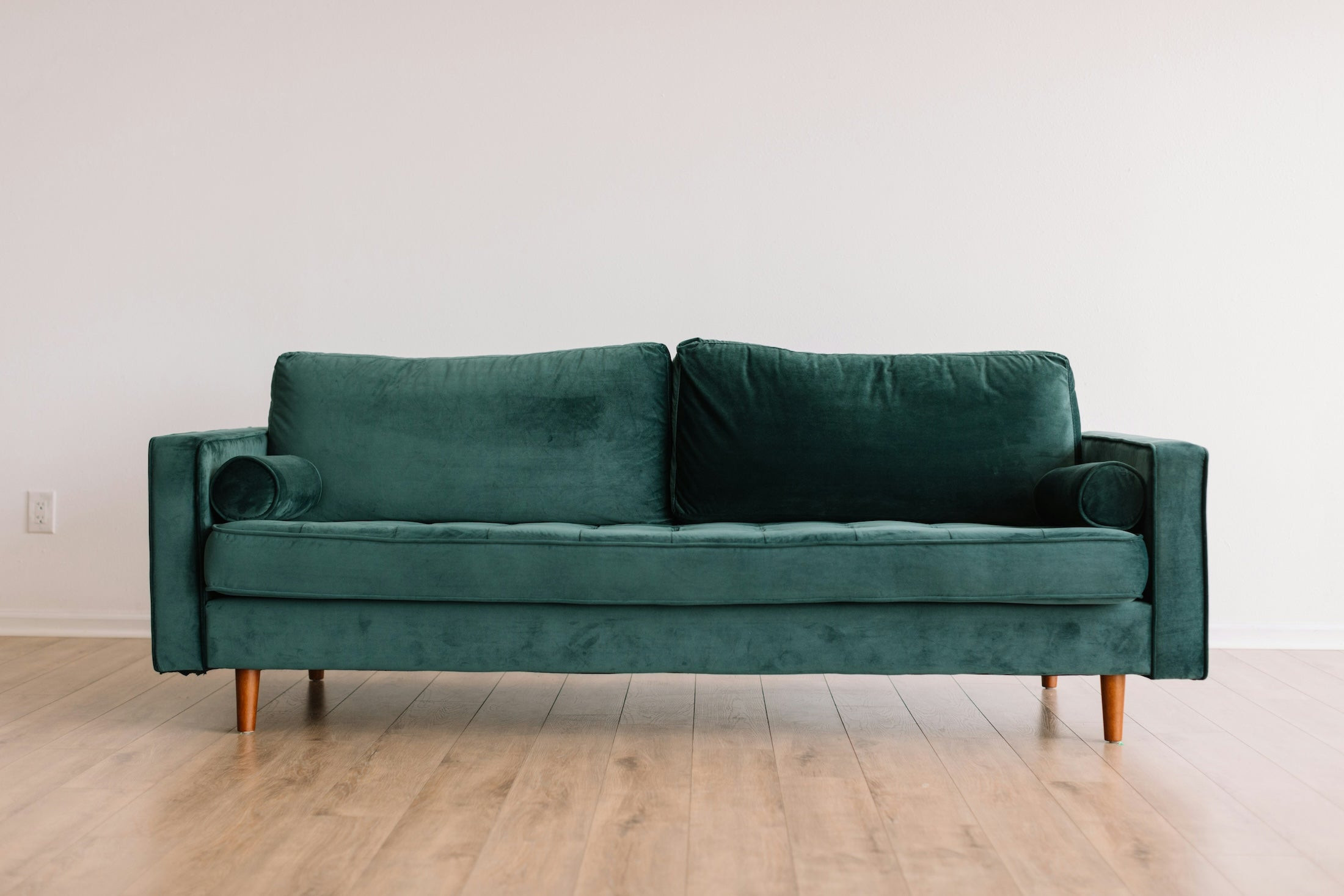 Green velvet sofa in an empty room