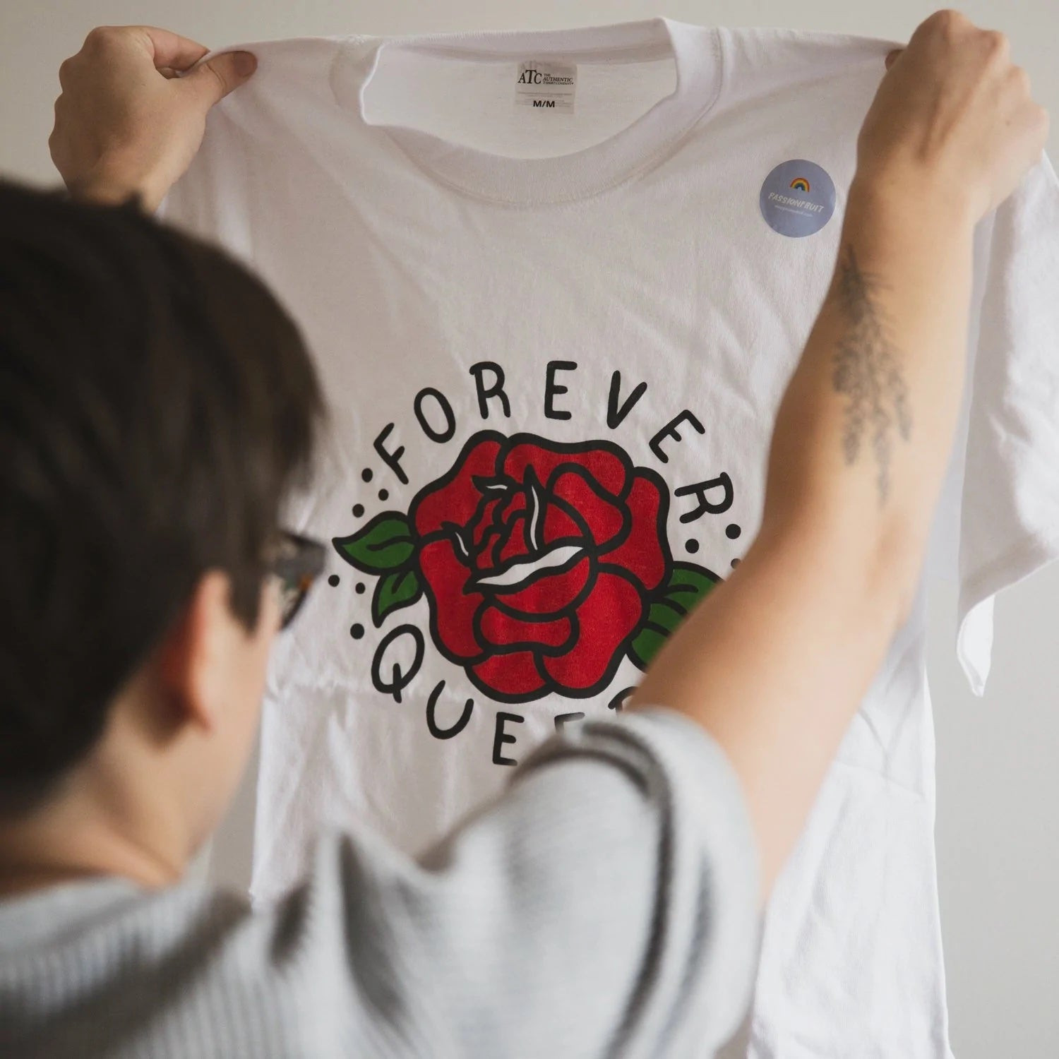 A person holds up a graphic t-shirt that reads Forever Queer