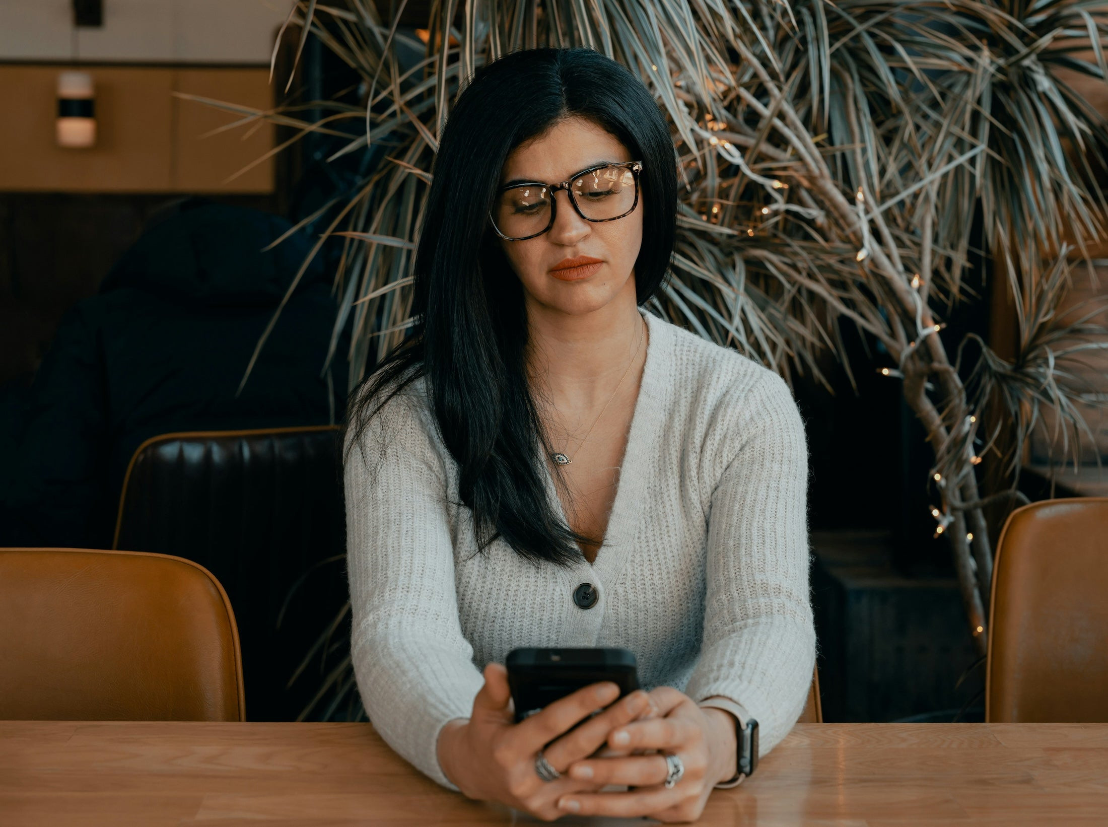 Person in white cardigan holding a smartphone