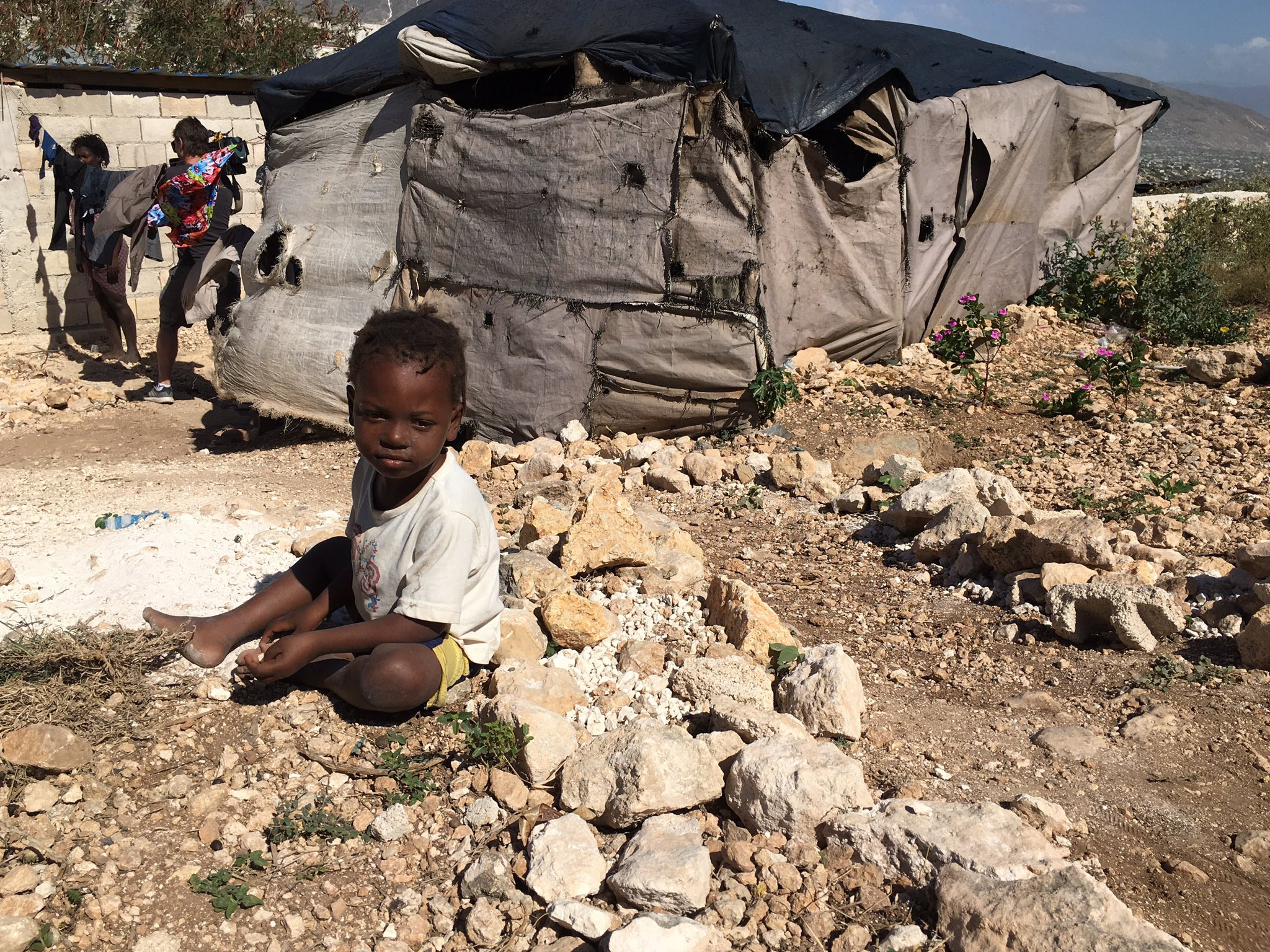 A small boy sits outside the tent he lives in with his family in Canaan, Haiti, January 2020. (Valerie Laillet)