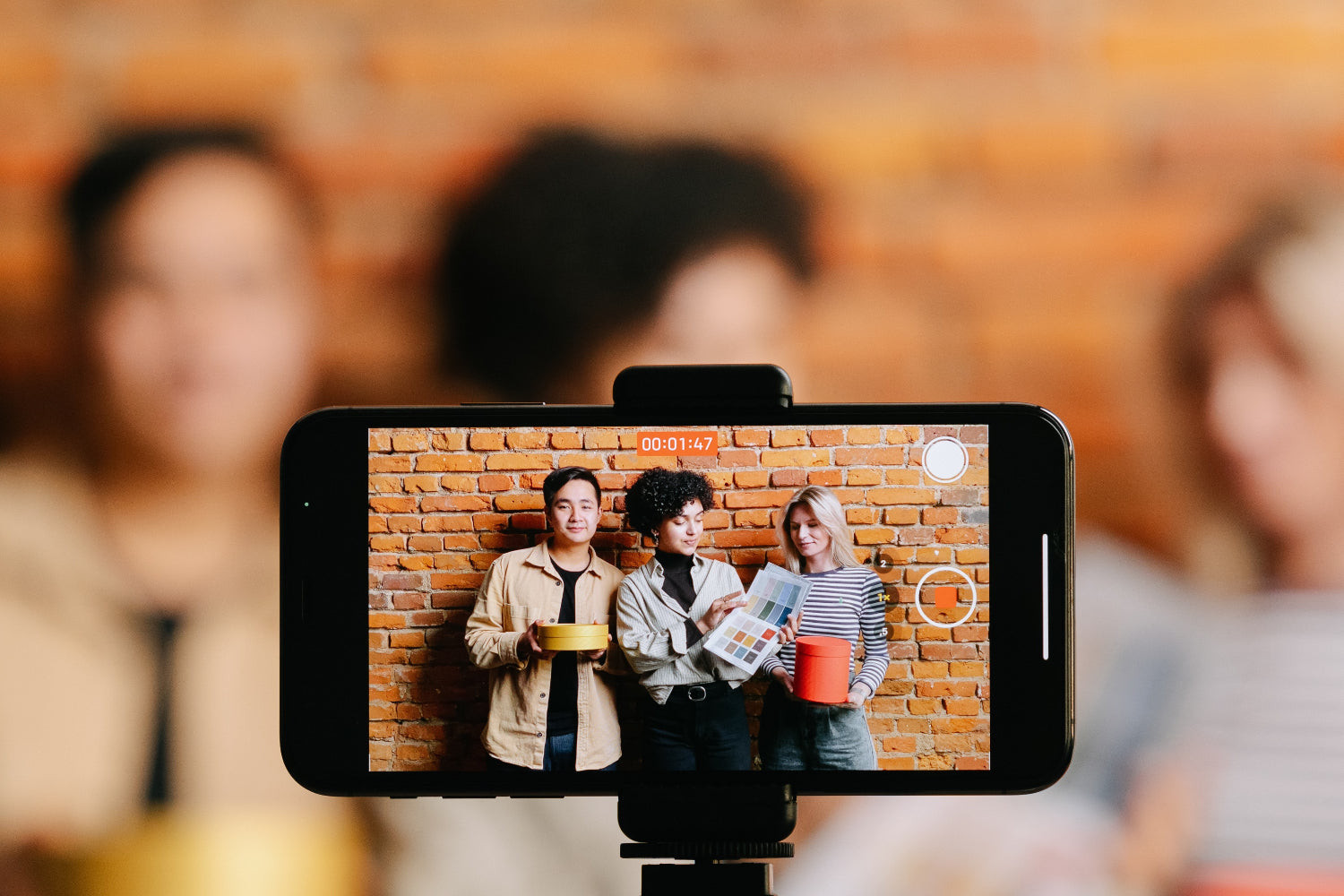 Three people hanging out by a brick wall